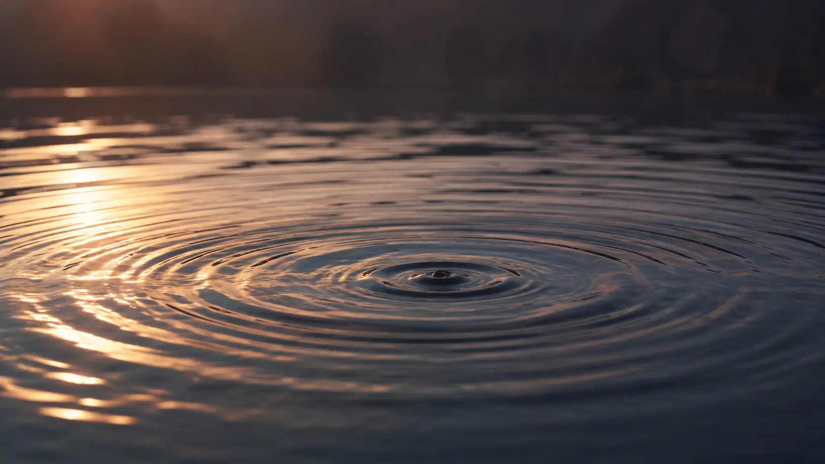 Ein Tropfen trifft auf eine ruhige Wasserfläche, feine Ringe laufen aus – Sinnbild für Gedanken, die kommen und gehen dürfen, in der Bewusstseinsarbeit von Andrea Schmucker